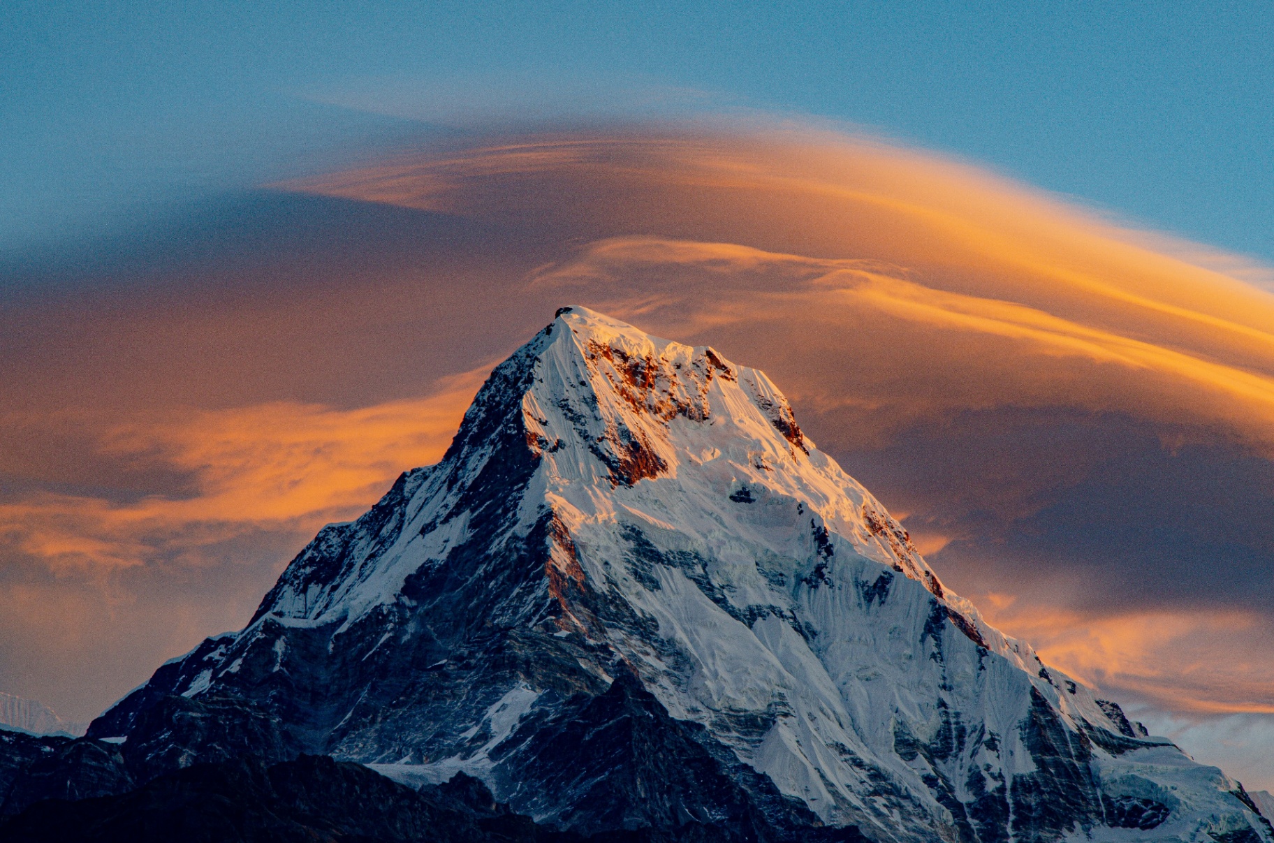 Schneebedeckter Berggipfel mit Wolke im Abendlicht